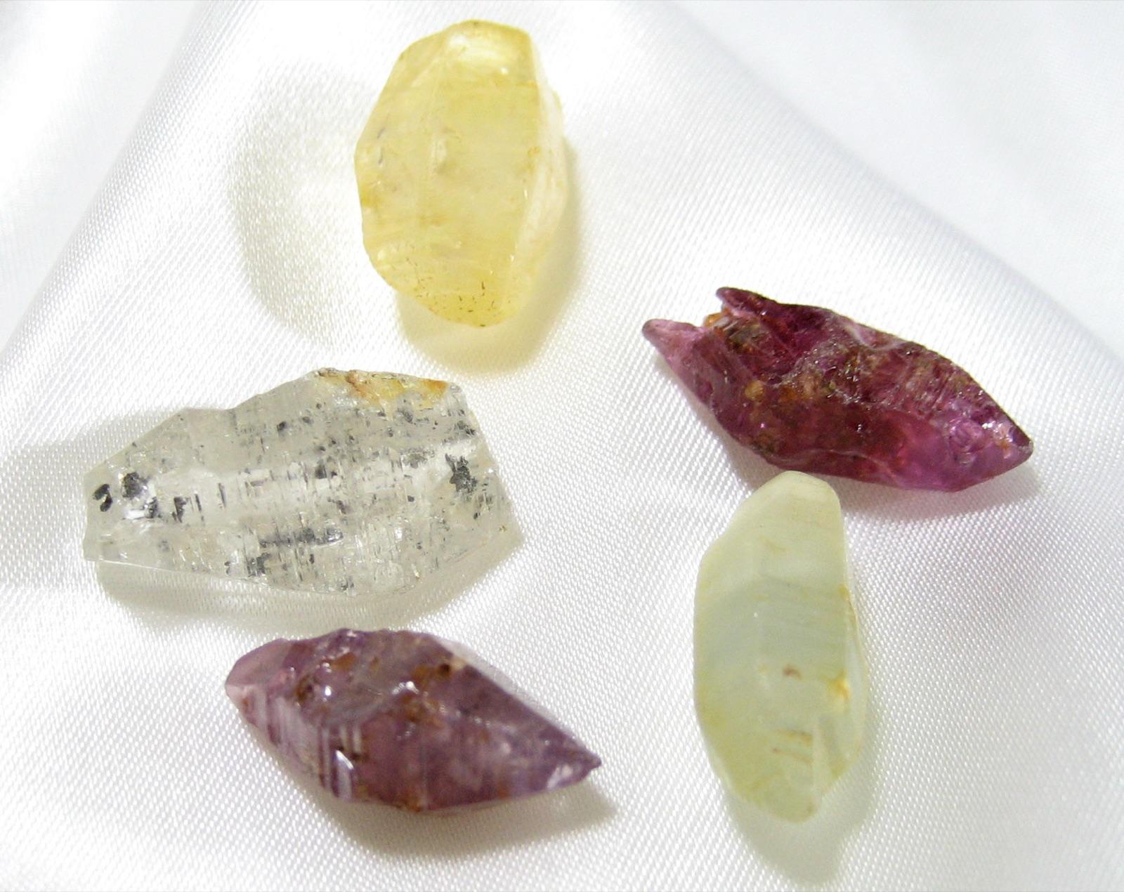 Rough corundum crystals in the pale yellow, purple and colourless range typical of gravel-bar sapphire