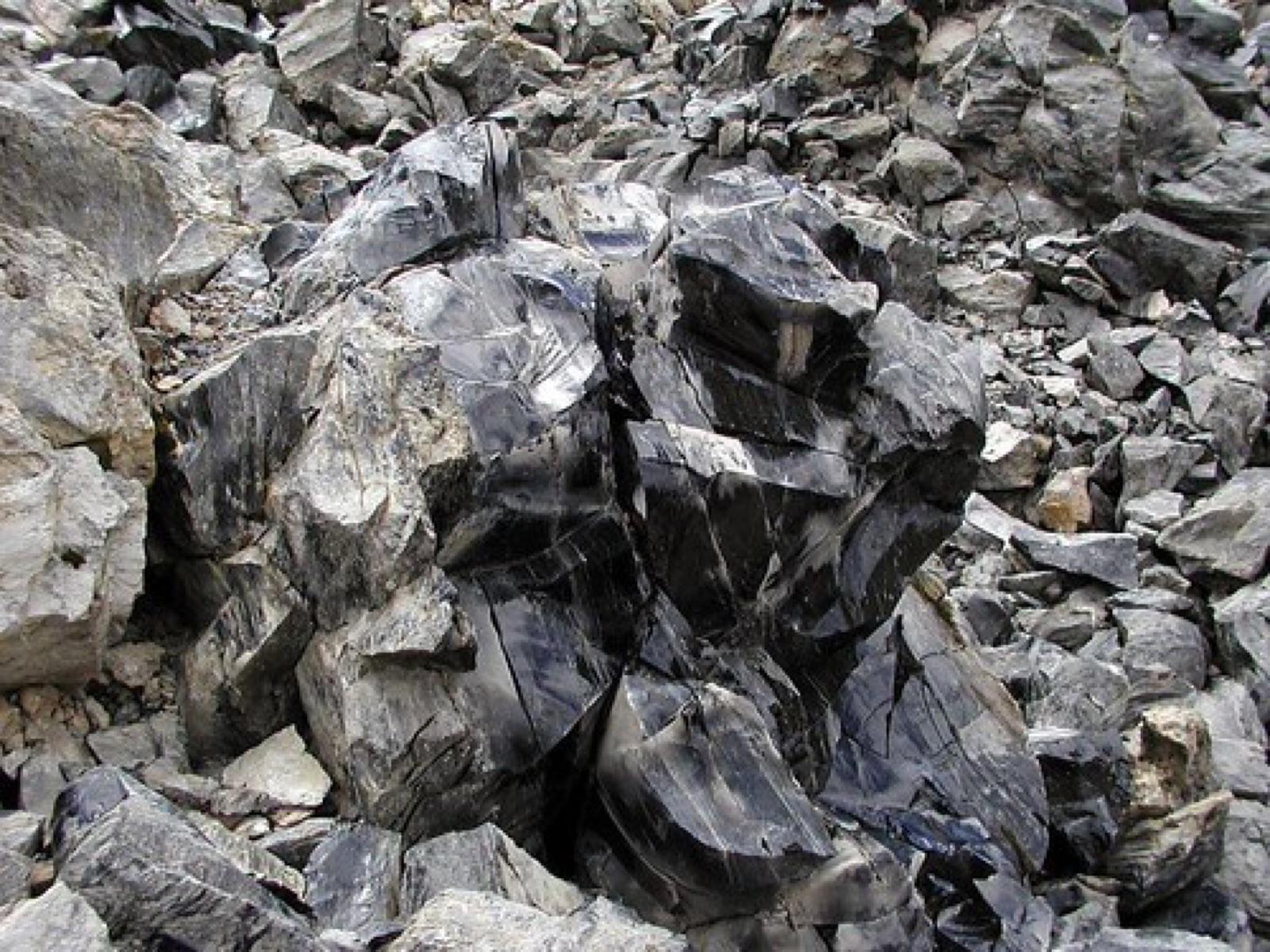 Obsidian in outcrop, broken into blocky glassy rubble