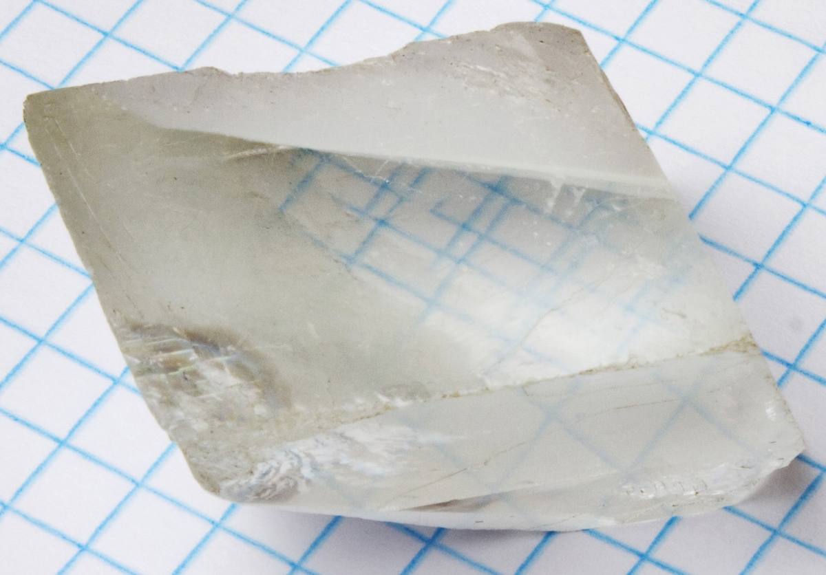Calcite cleavage rhomb on graph paper showing birefringence