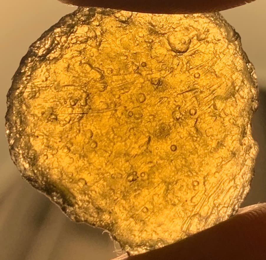 Georgiaite tektite found in Dodge County, the olive-green natural glass held up to the light