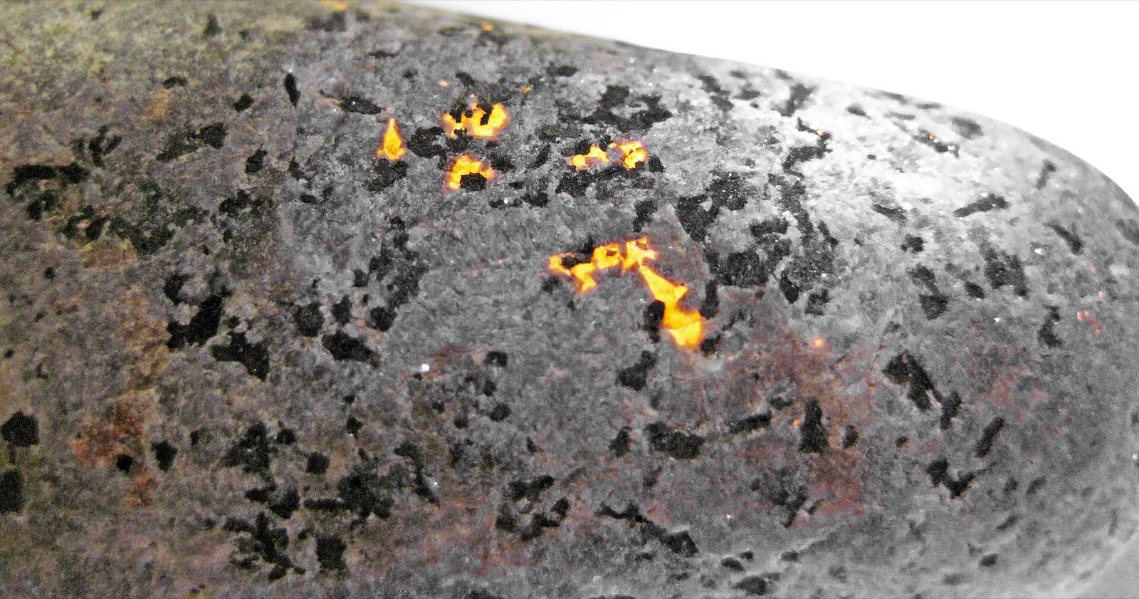 A Yooperlite glowing orange under ultraviolet light, found on the Lake Superior shore near Grand Marais