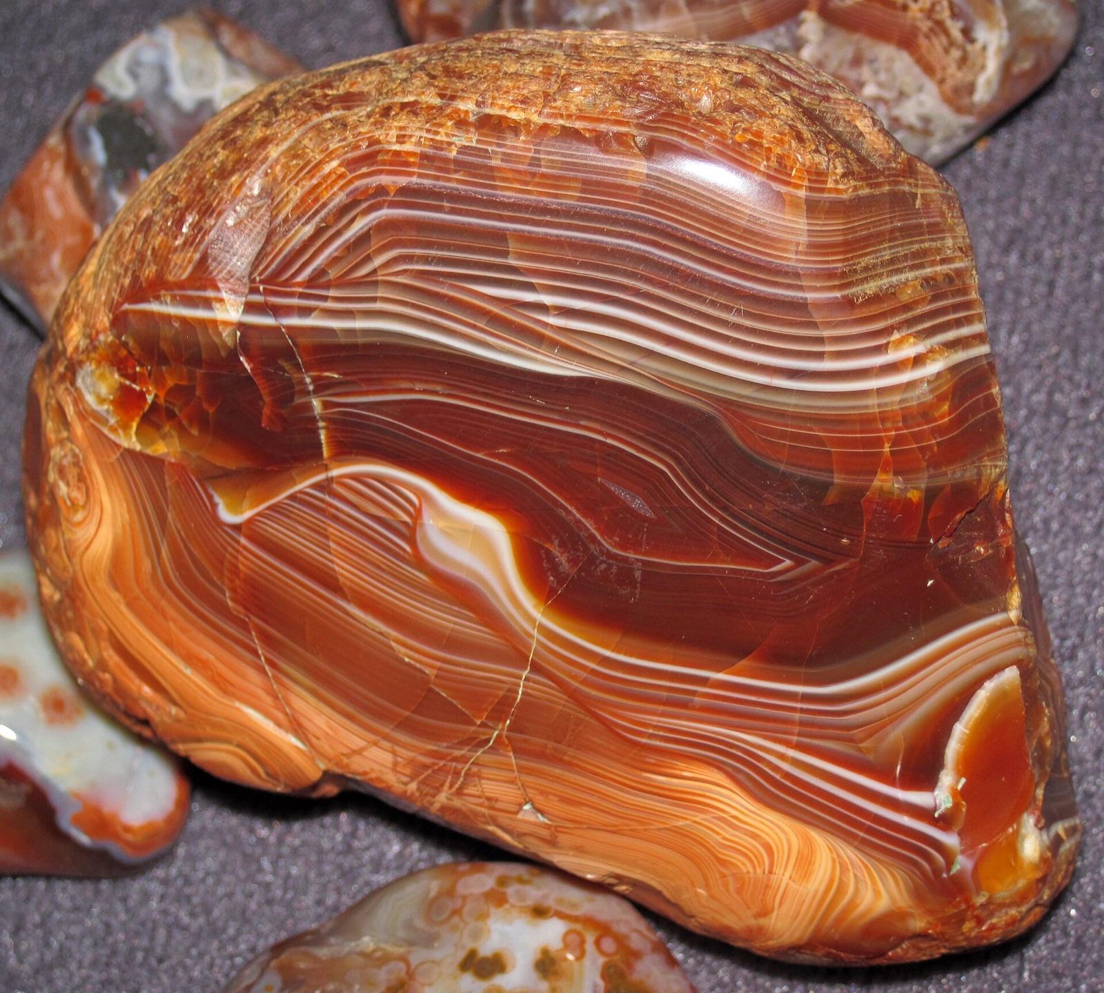 A polished Lake Superior agate showing red and orange fortification banding, the ice carried agate type that turns up tumble rounded in Daviess County glacial drift and Grand River gravels.