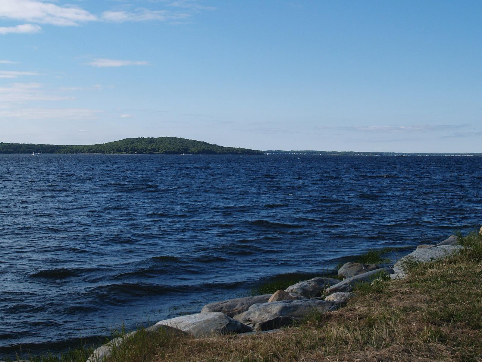 The rocky shore of Mt. Hope Bay seen from Common Fence Point, Rhode Island, with Mount Hope rising across the water.