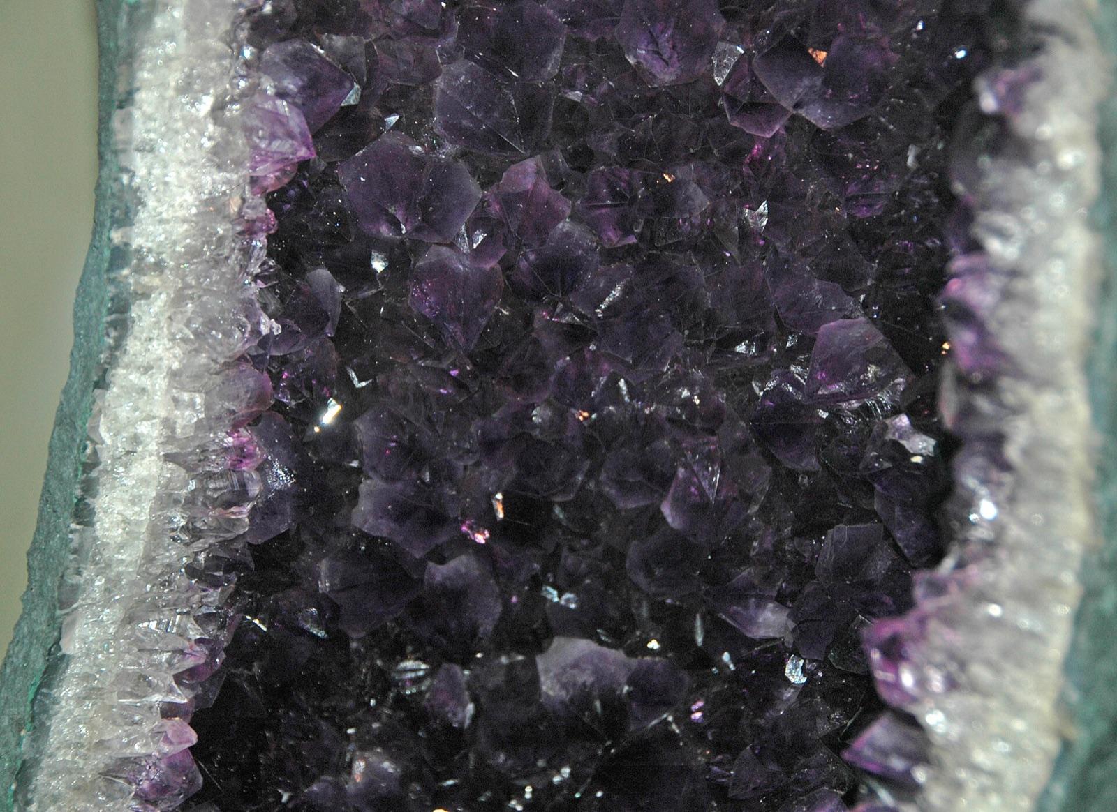 The interior of an amethyst geode packed with deep-purple quartz crystals behind a white chalcedony rim, the crystal-lined geode prized along Whitewood Creek